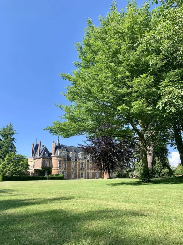 Château de Miromesnil vu depuis le parc arboré, avec grande pelouse et arbres centenaires en Normandie