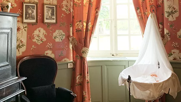 Chambre historique du Château de Miromesnil avec berceau blanc, fauteuil ancien et décor floral